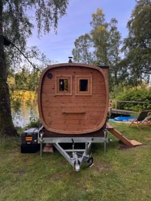 Widok z przodu mobilnej sauny TimberIN Nordic Square na przyczepie nad jeziorem